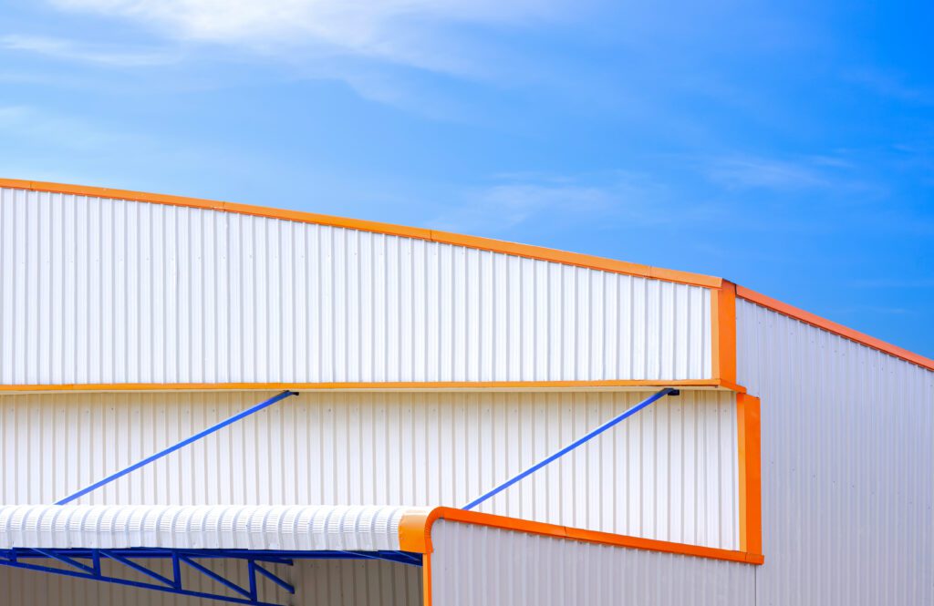 White corrugated aluminum industrial warehouse building with awning in modern style against blue sky