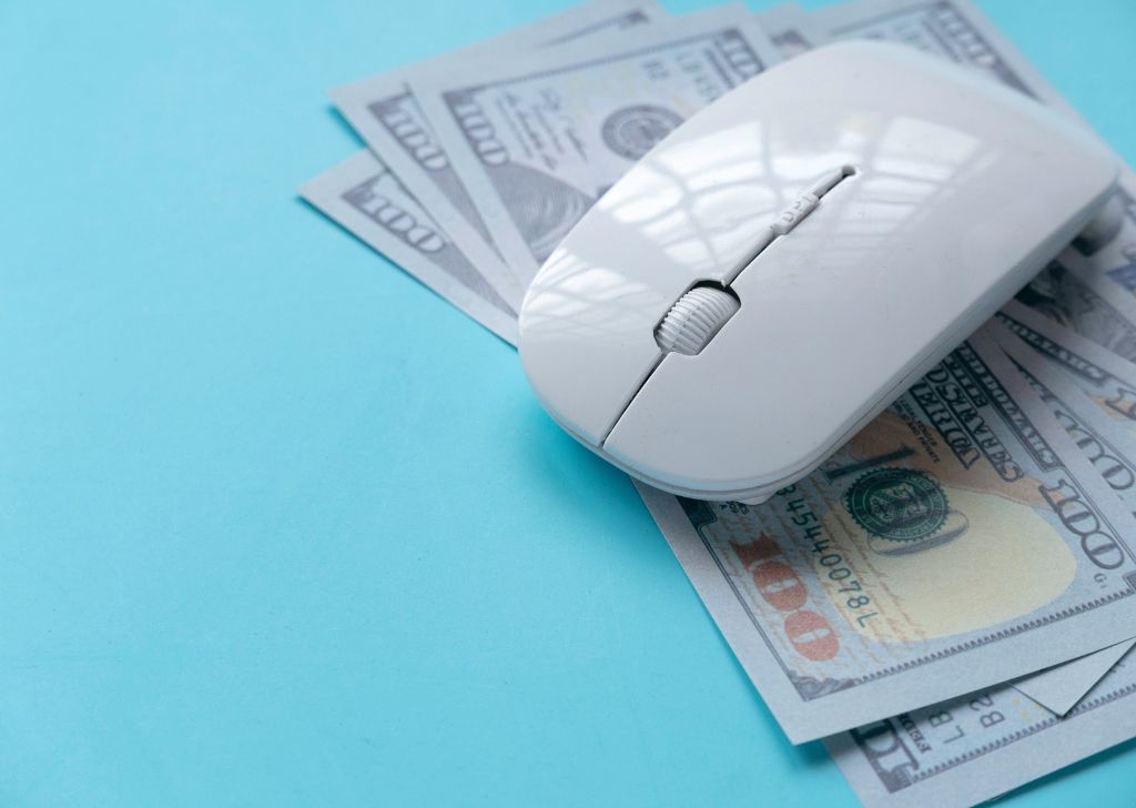 A mouse placed on top of money used to symbolize PPC marketing. 