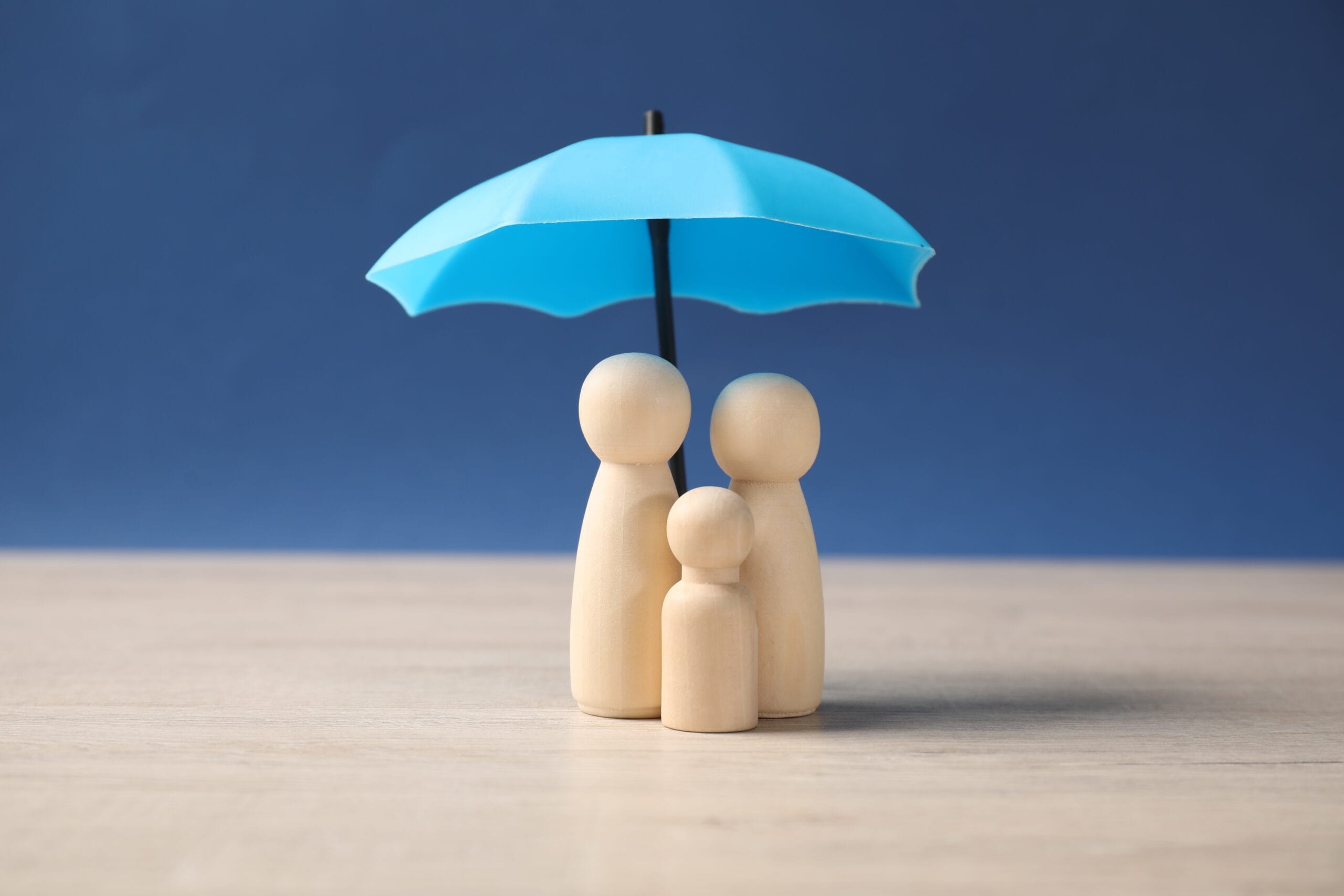 family wooden figure under blue umbrella