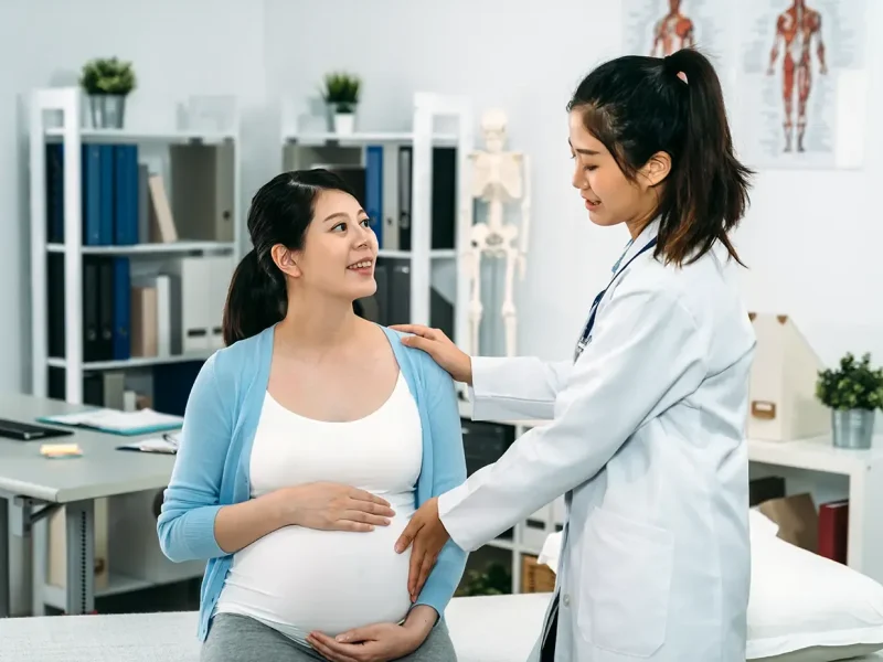 asian-pregnant-mother-sitting-treatment-bed-is-smiling-female-doctor-while-she-is-touching-her-belly-checking-baby-s-health-hospital-copy